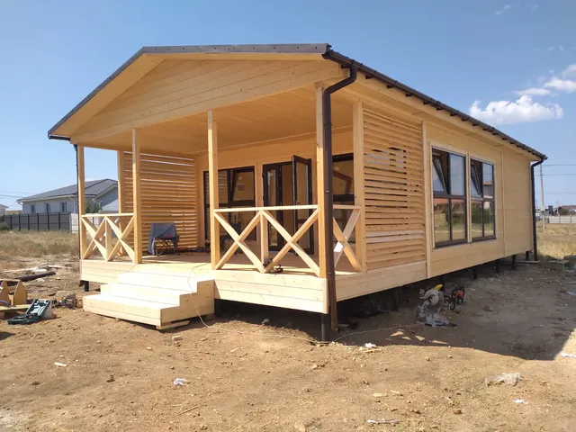 Деревянный дом с крытой террасой, перекрёстными перилами и лестницей