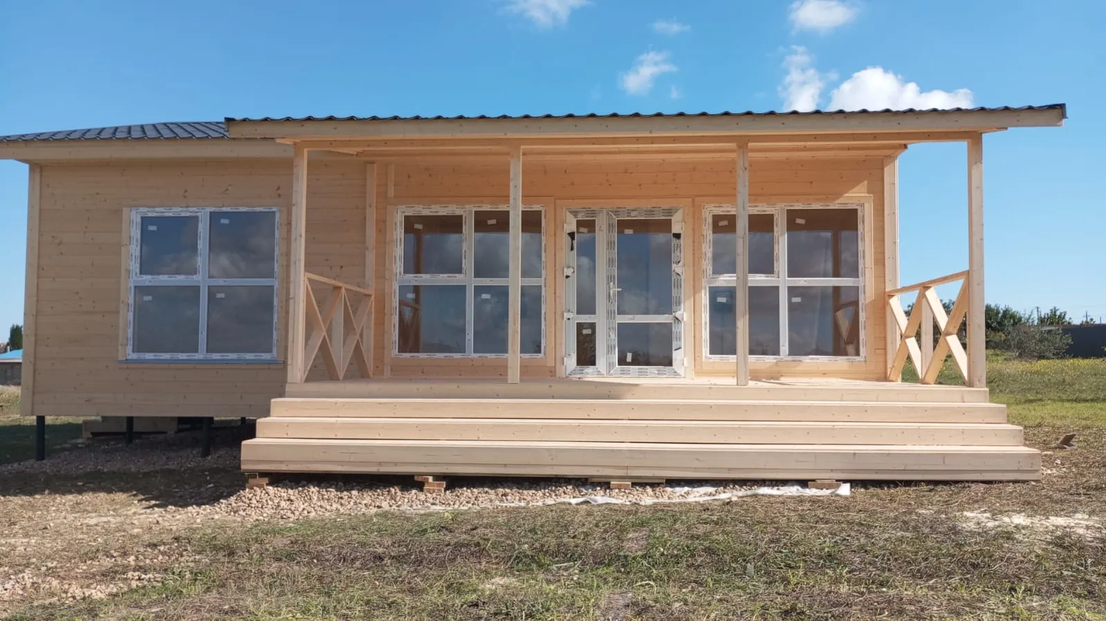 Деревянный дом с длинной крытой террасой и большими окнами