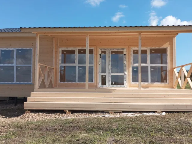 Деревянный дом с длинной крытой террасой и большими окнами